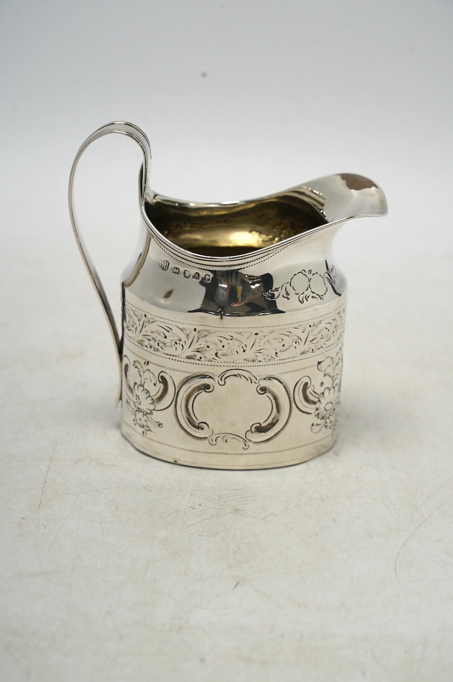 A George III silver cream jug, with later decoration, Robert & David Hennell, London, 1796, 10.4cm, 3.5oz. Condition - poor to fair